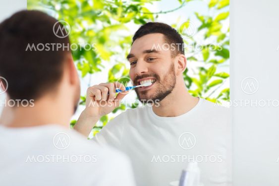man with toothbrush cleaning teeth at bathroom