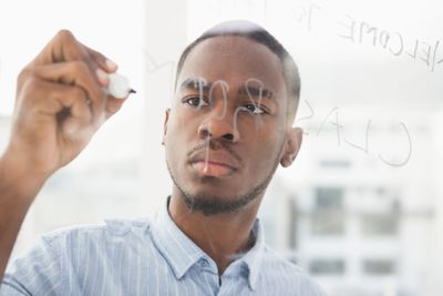 Focused businessman writing on clear board 