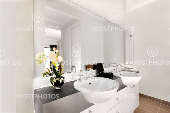 Close view of a modern bathroom included a big mirror and white washstands