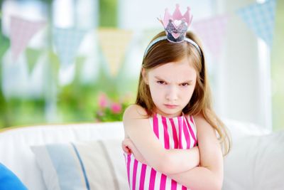 Moody little girl wearing princess tiara feeling angry...