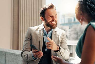 Conversation, smartphone and business people in city,...