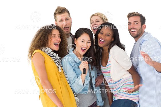 Happy group of young friends having fun doing karaoke