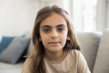 Close up photo of cute little girl sitting on couch