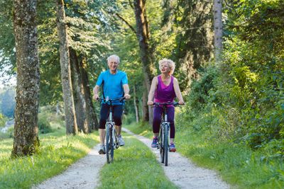Happy and active senior couple riding bicycles outdoors...