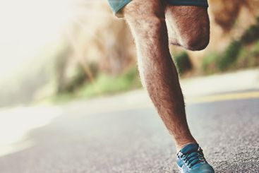 Running, fitness and legs of man in street for exercise,...