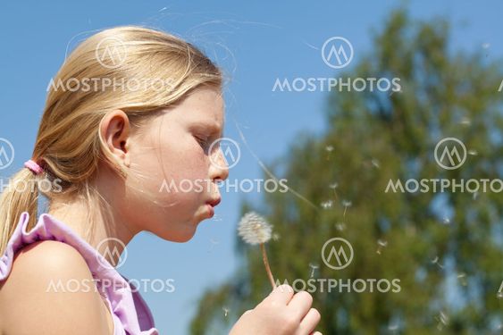 Teenager girl puffing to dandelion