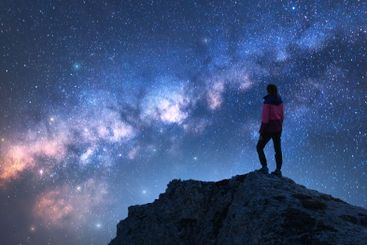 Glowing Milky Way and woman on mountain peak at starry...