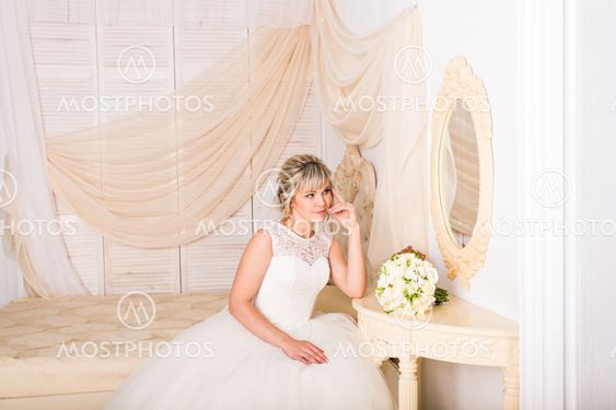 portrait of happy young woman in white wedding dress and...