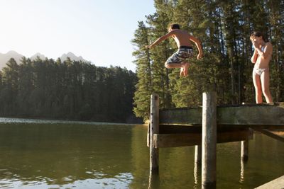 Two Children Jumping From Jetty Into Lake