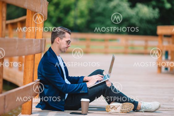 Young man with laptop working outdoors