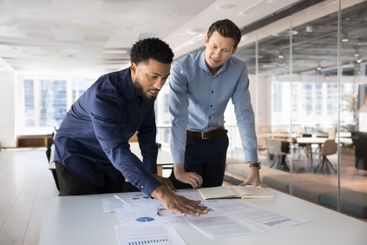 Two male diverse business partners analyzing project...