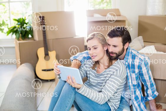 Couple sitting on floor and using digital tablet