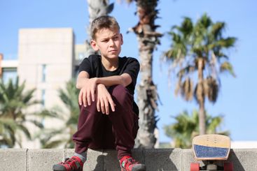 Handsome teenager sitting with skateboard. Adolescent...