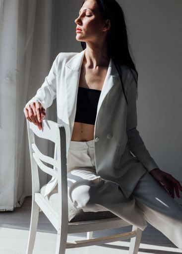 Beautiful slim brunette woman in jacket sitting on chair