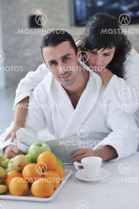 Happy couple reading the newspaper in the kitchen at breakfast