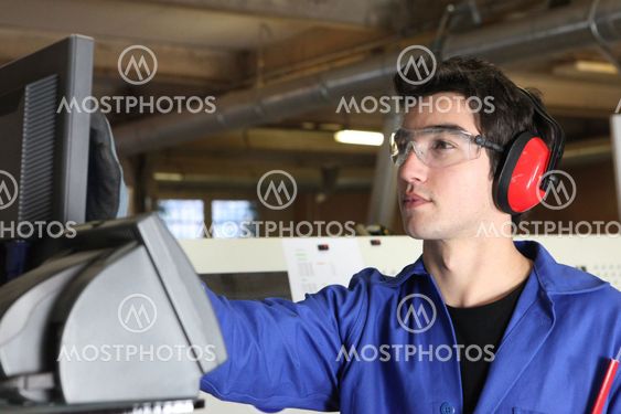 Young man operating machine in factory