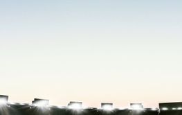 Empty large football field with flashlights and sunny...