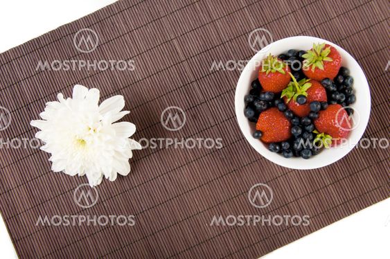 strawberries, bilberry and flower on bamboo tablecloth