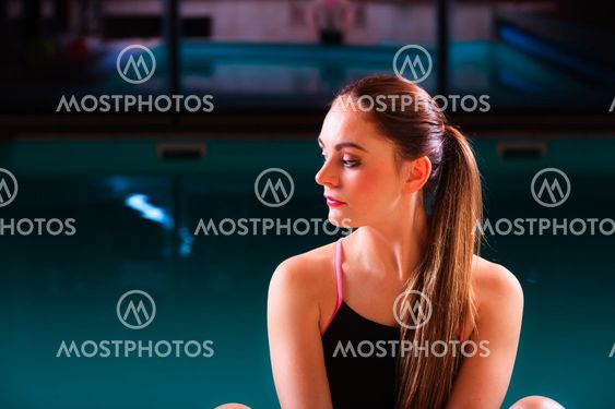 Sporty fit woman at swimming pool edge poolside.