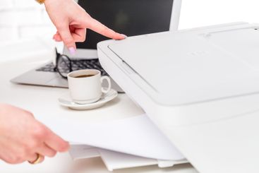 Person scanning documents at a desk with a computer and...