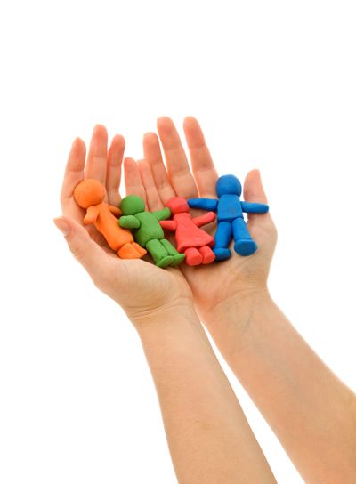 Hands folding colorful clay people
