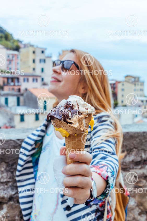 Young woman holding icecream in Manarola in the UNESCO...