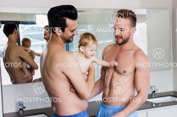 Happy gay couple holding their child