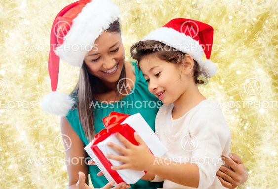 happy mother and girl in santa hats with gift box