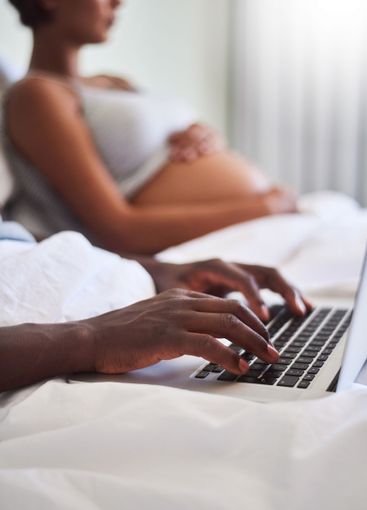 Hands, laptop and pregnant with couple in bed together...
