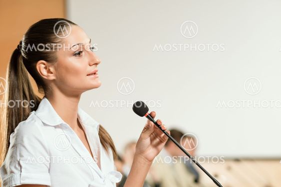 Business woman speaks into a microphone