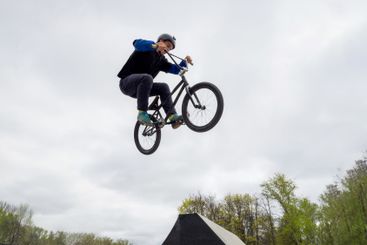 BMX bicycle rider doing trick jump over spine