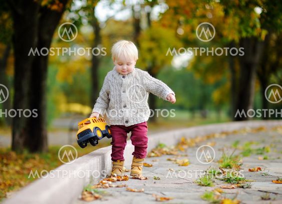 Toddler playing with toy car in autumn park