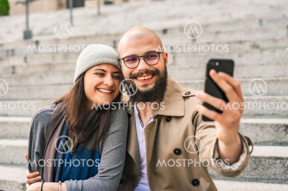 Smiling young couple taking selfie with smartphone