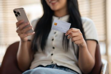 A satisfied Asian woman sitting indoors, enjoying the...