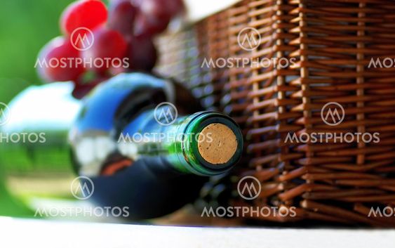 red wine in bottle and basket of grape