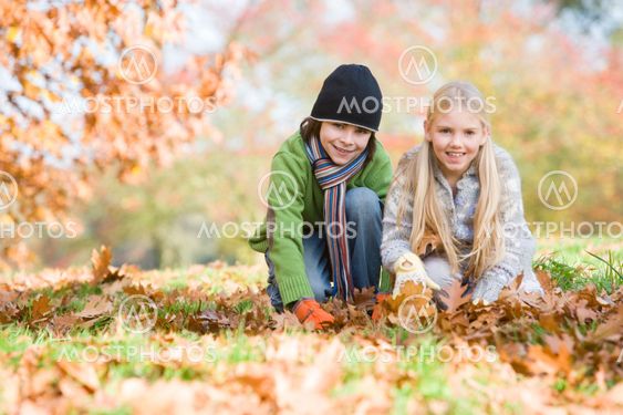 Two children collecting leaves