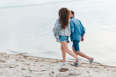 back view of young couple running on seashore
