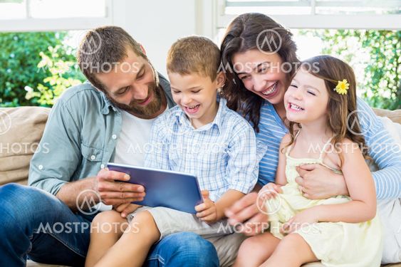 Parents and kids using digital tablet in living room