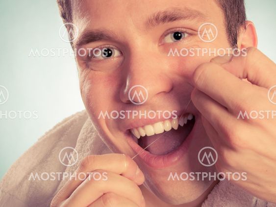 Young man cleaning her white teeth with dental floss