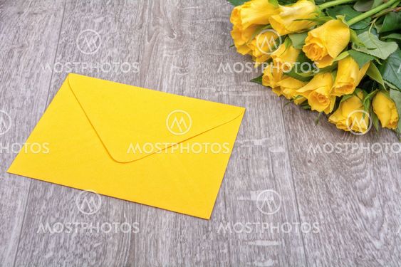 Yellow envelope and roses on a wooden background