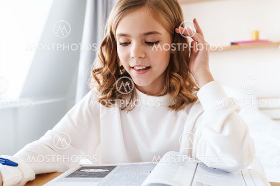 Photo of focused girl writing in exercise book while...