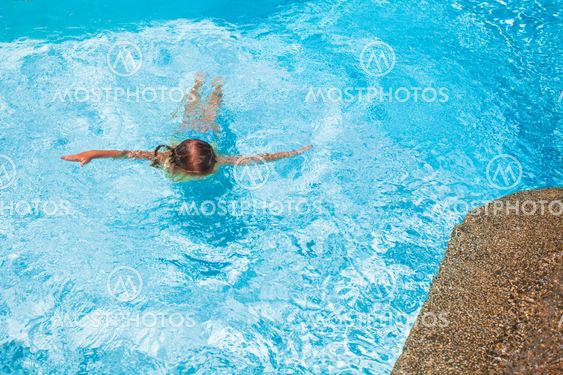 Little cute girl swims in the swimming pool at exotic resort