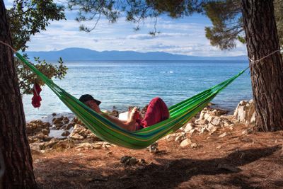 Man läser bok i hängmatta på strand