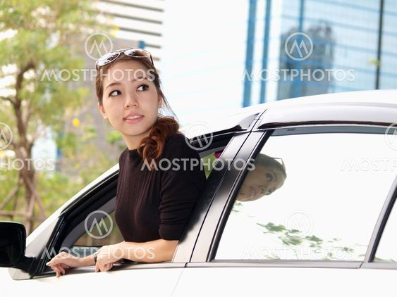 Young pretty Asian girl looking at back of car