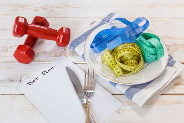 Fitness concept with dumbbells and measuring tape