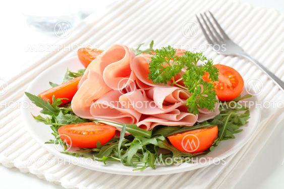 Sliced ham with arugula leaves and tomatoes