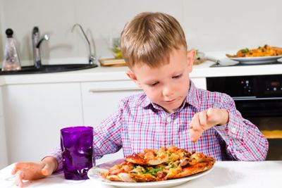 Little boy eating a big plate of pizza