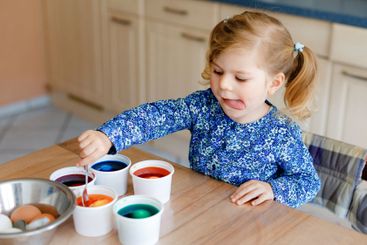 Excited little toddler girl coloring eggs for Easter....