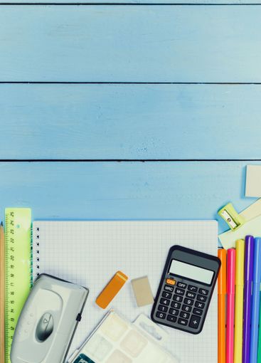 Office supplies arranged neatly on a blue wooden table,...