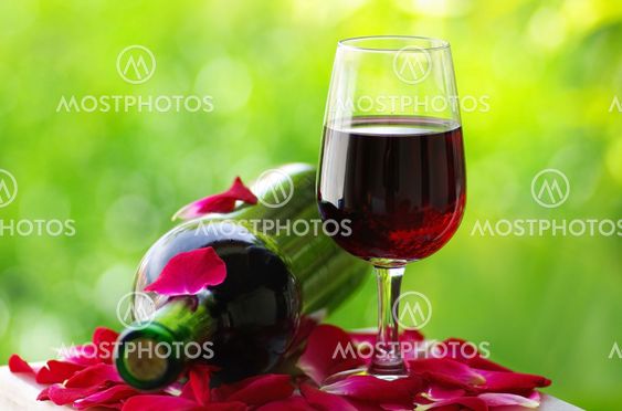 Petals of rose in a glass of red wine.